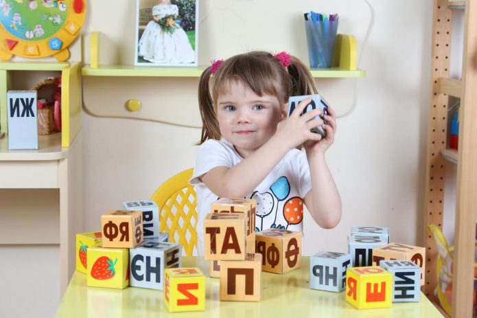 Девочка держит кубики с буквами