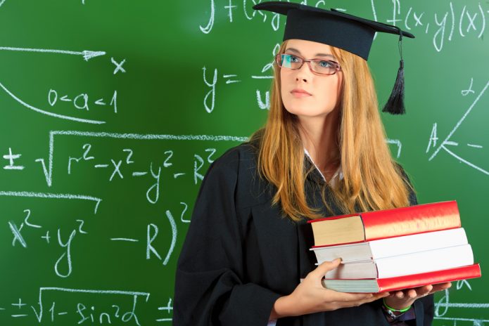 Девушка в мантии и академической шапочке со стопкой книг в руках
